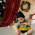 Bé đội mũ đen ngồi trong bối cảnh Giáng sinh