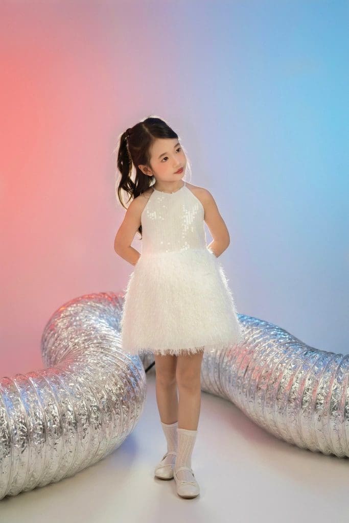 Bé quay nhìn qua vai cạnh các ống trang trí màu bạc