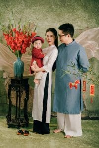 Ba mẹ mặc áo dài trắng xanh cùng nhìn bé áo dài đỏ