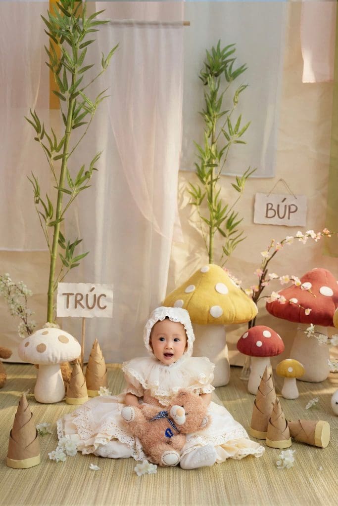 Ảnh từ trên xuống bé nằm giữa nấm trang trí và bảng tên Búp