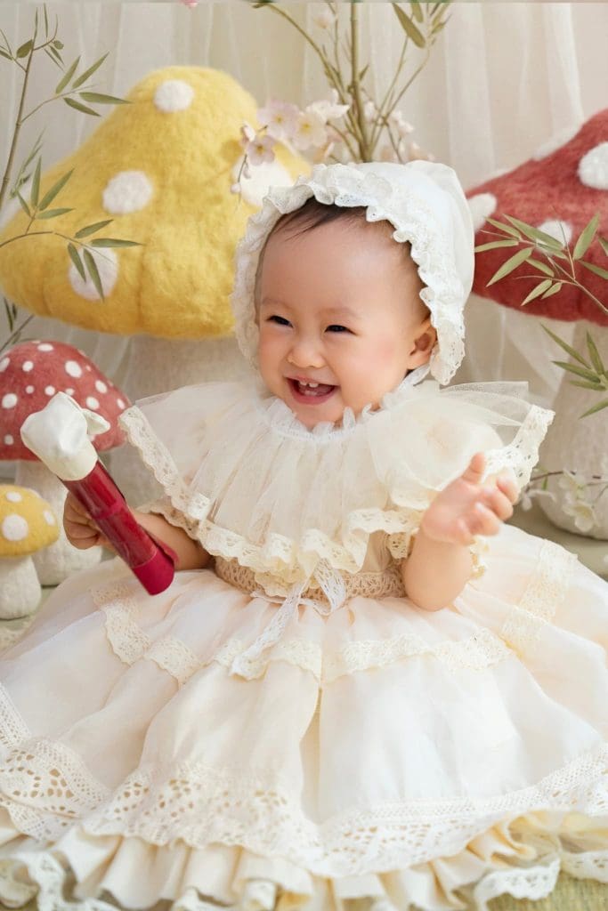 Chân dung bé cười, đội mũ viền bèo màu trắng