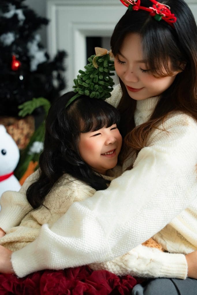 Chụp ảnh Noel tại TP.HCM: chuẩn bị theo địa điểm và lịch của gia đình 1 Mẹ ôm bé gái mặc váy đỏ trong bối cảnh Noel