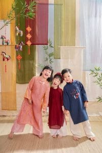 Ba bé ngồi gần nhau trong trang phục áo dài