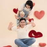 Ba mẹ và bé tạo dáng trong bối cảnh trái tim đỏ