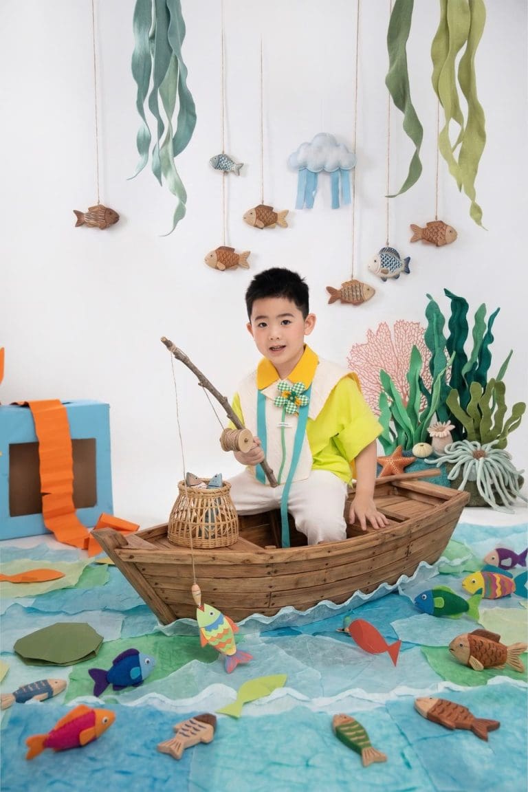 Bé ngồi trong thuyền gỗ giữa bối cảnh đại dương bằng giấy